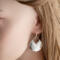  Side view of a person wearing a sterling silver hammered pear dangle earring, showcasing the design and ear wire.

